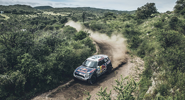 Rally car on the Red Bull Dakar rally driving through a green landscape 